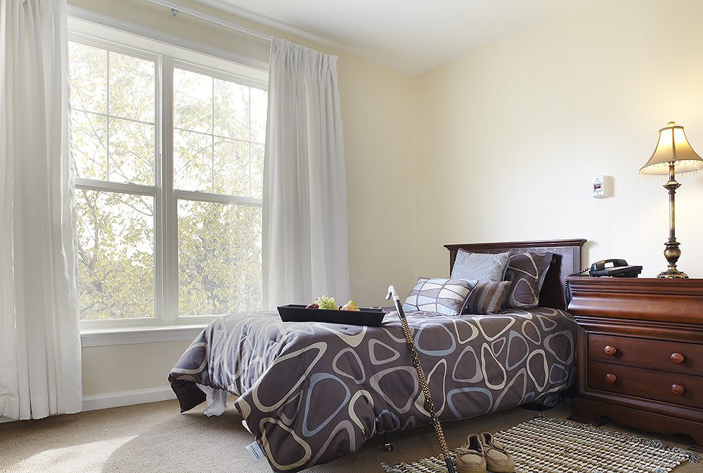A cozy bedroom with a single bed and large window letting in natural light.