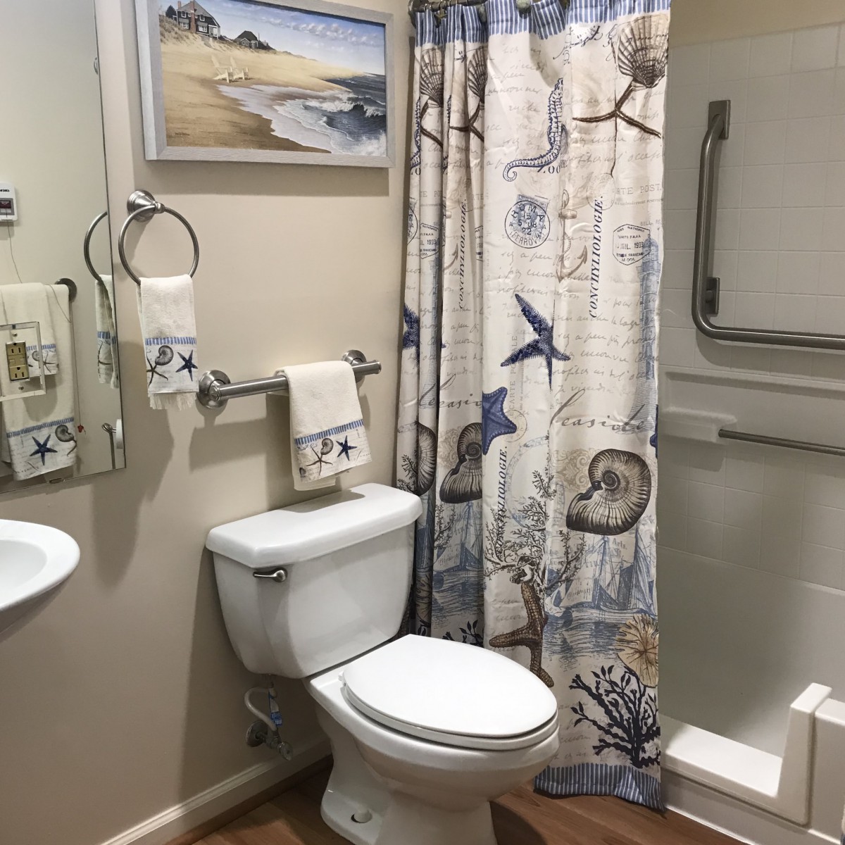 A nautical-themed bathroom with a shower, toilet, and decorative elements.