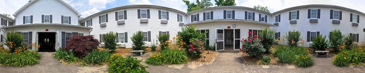 A charming house with a lush garden in front, featuring vibrant flowers and greenery.