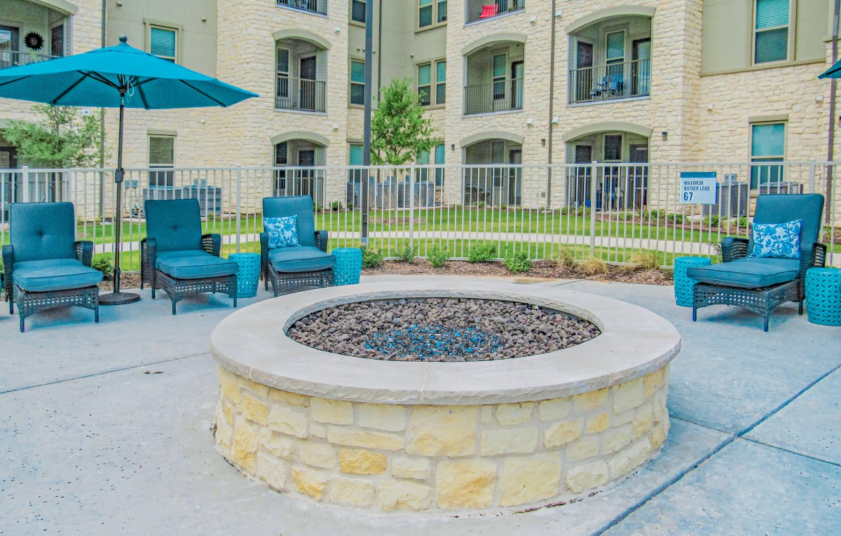 An outdoor fire pit surrounded by comfortable seating in the courtyard of an apartment complex.