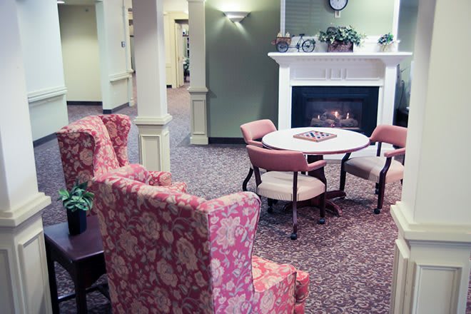 A cozy indoor seating area with a fireplace, table, and chairs.
