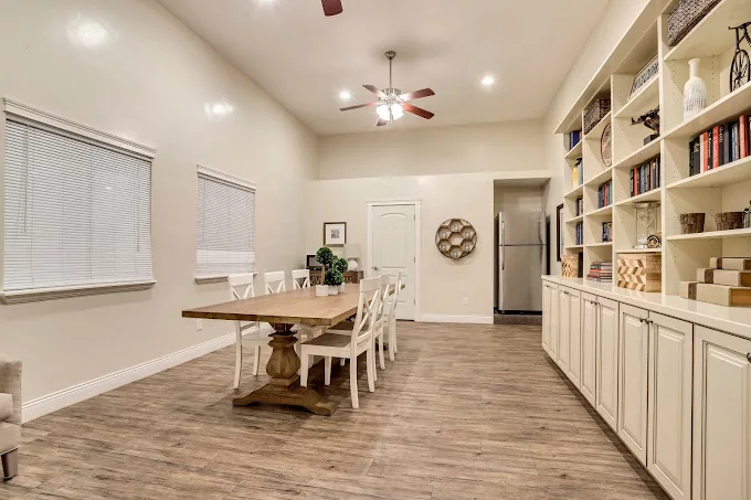 A spacious dining room with a wooden table, chairs, and built-in bookshelves.