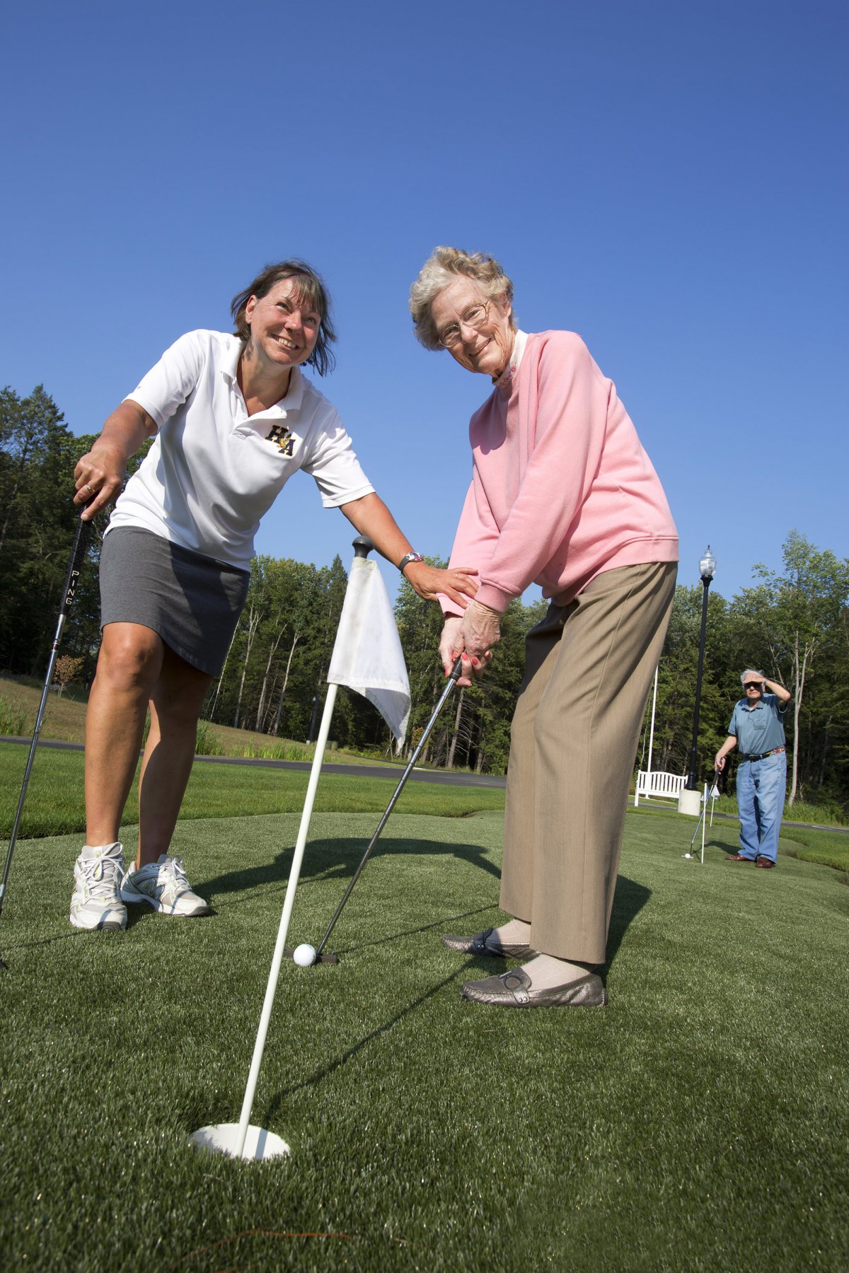 Two women enjoying a golf lesson on a sunny day.