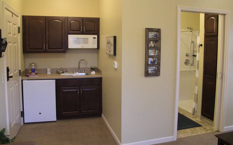 A small kitchen area featuring dark cabinets, a white microwave, and a sink.