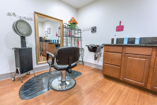 A cozy and well-organized hair salon interior with a barber chair, mirror, and various styling products.