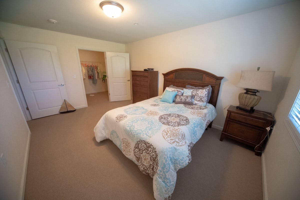 A cozy bedroom with a neatly made bed and wooden furniture.