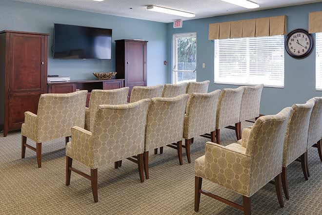 A small conference room with rows of chairs facing a TV.