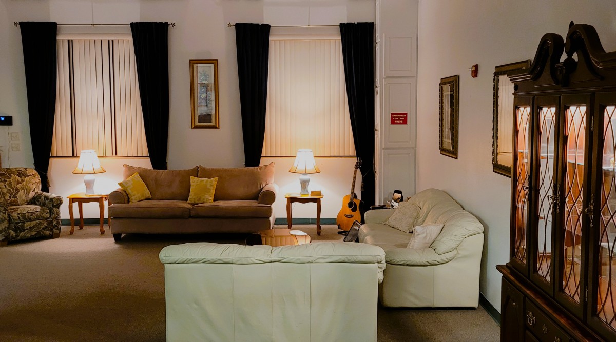 A cozy living room with two sofas, a guitar, and a lamp softly illuminating the space.