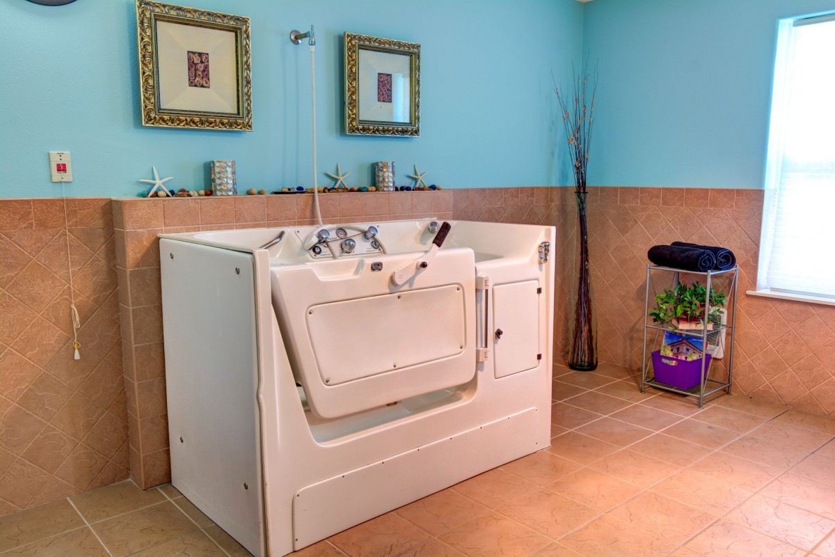 A modern bathroom featuring an accessible walk-in bathtub with blue and beige decor.