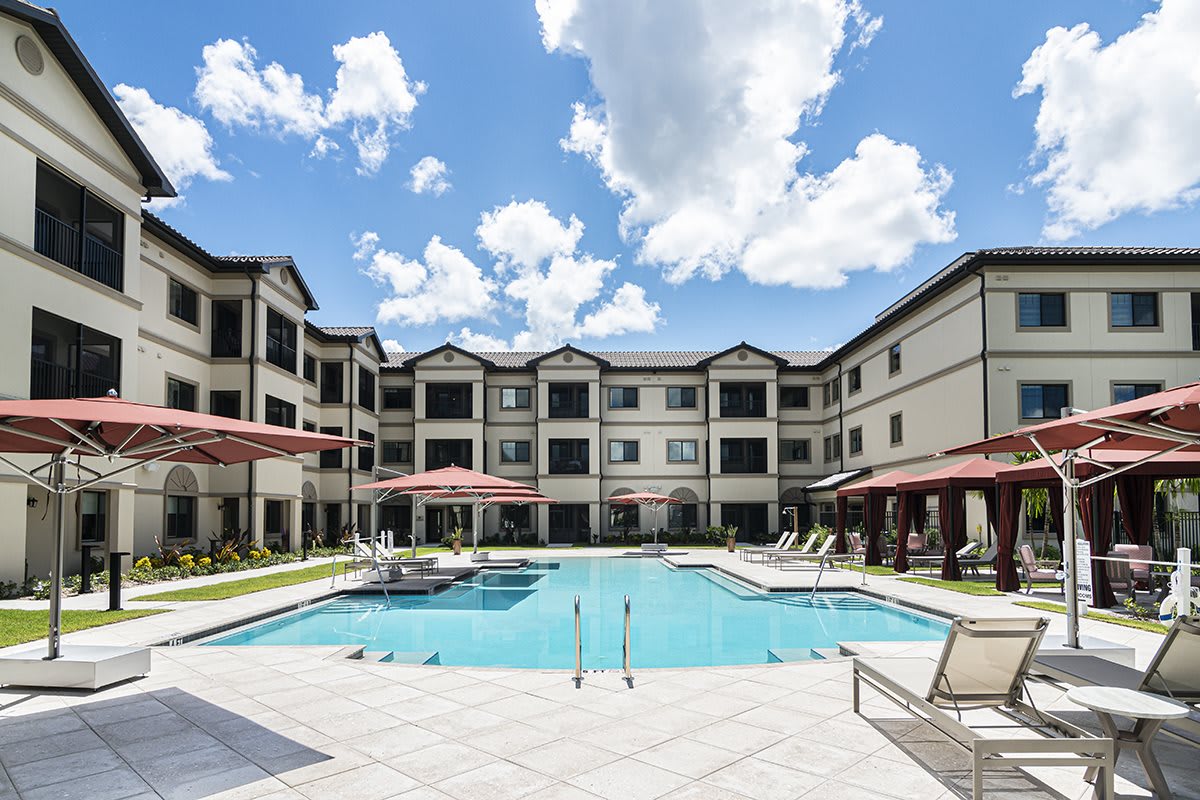 An outdoor swimming pool surrounded by a residential apartment complex on a sunny day.