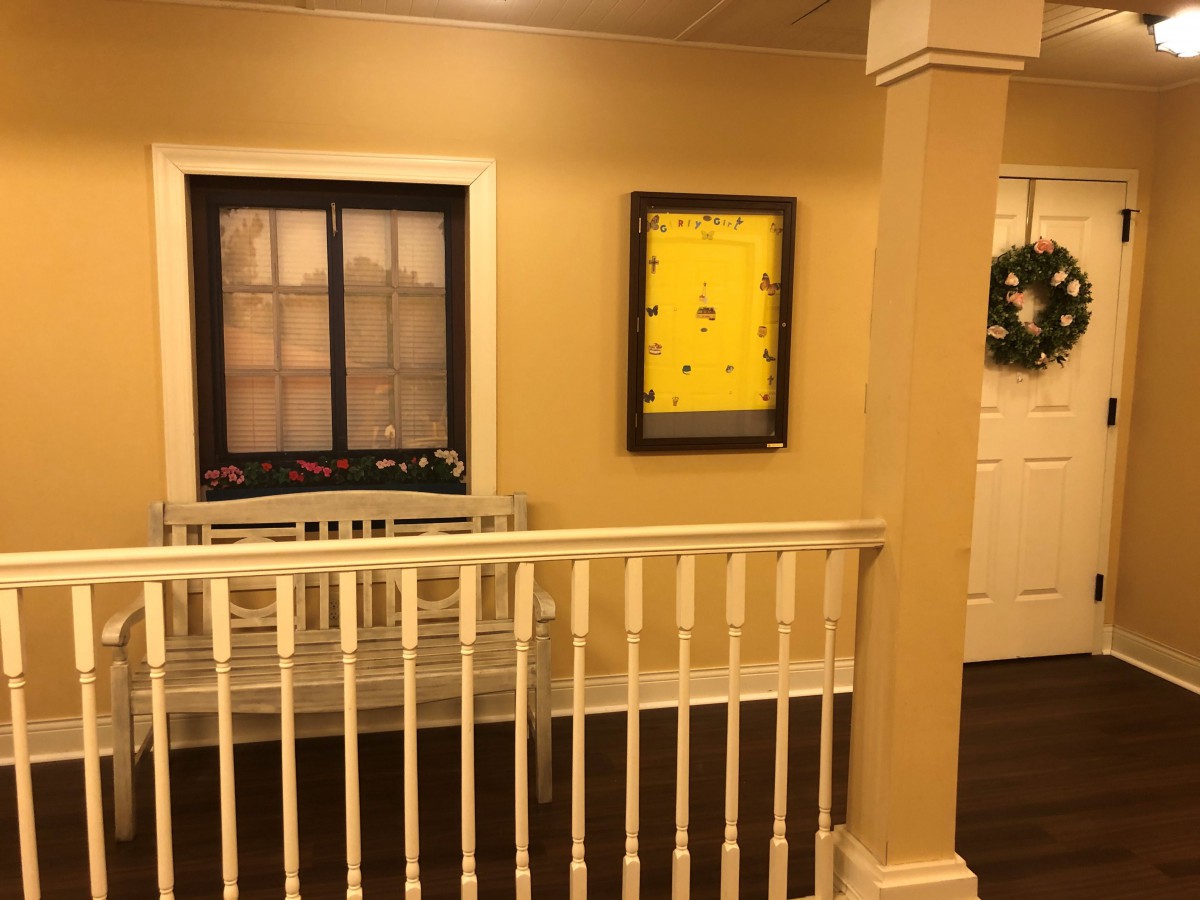 A hallway with a railing, featuring framed artwork and decor.