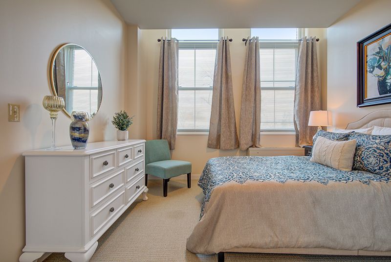 A cozy bedroom with a stylish dresser and large windows.