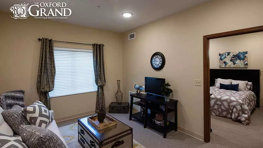 A cozy living room interior with a small TV setup, decorative vases, and a wall clock.