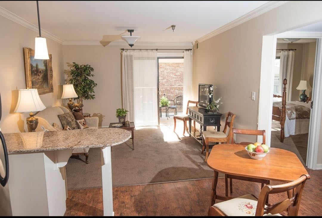 A cozy living and dining area with natural light, featuring comfortable seating, a TV, and stylish decor.