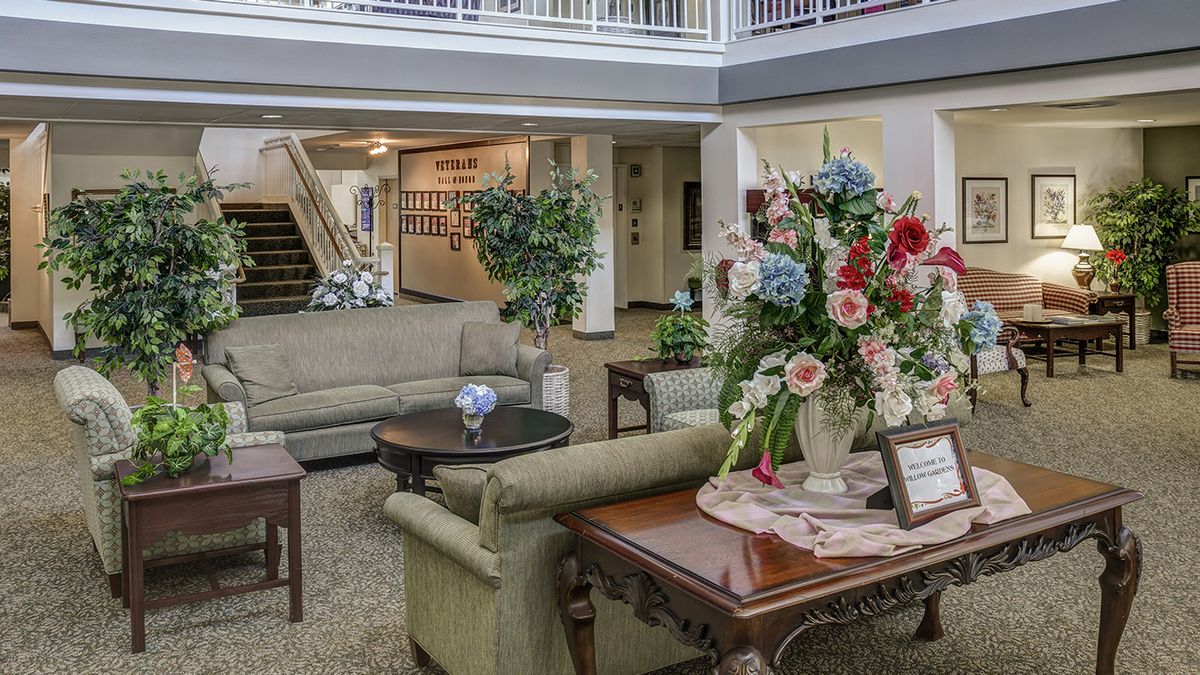 A cozy lobby area featuring comfortable seating, a large floral arrangement on a table, and an elegant staircase.