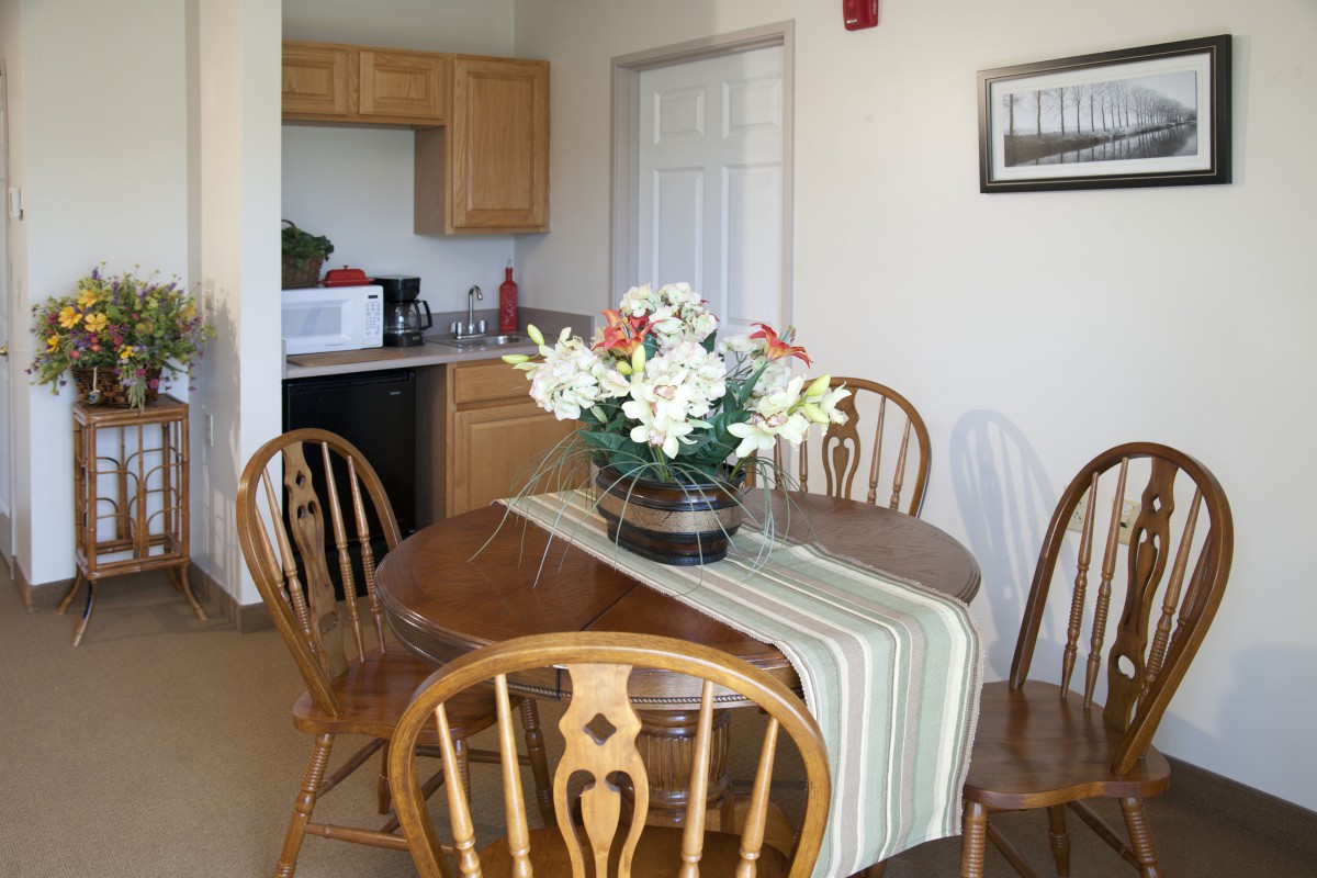 A cozy dining area with a wooden table, surrounded by chairs and adorned with a floral centerpiece.