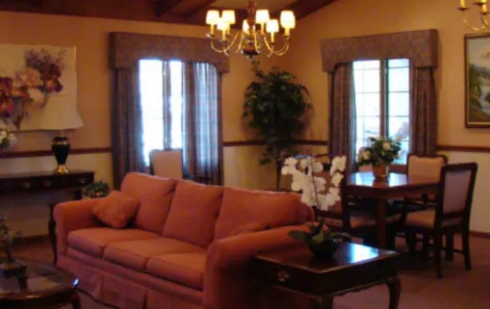 A cozy living room with a sofa, chandelier, and dining area.