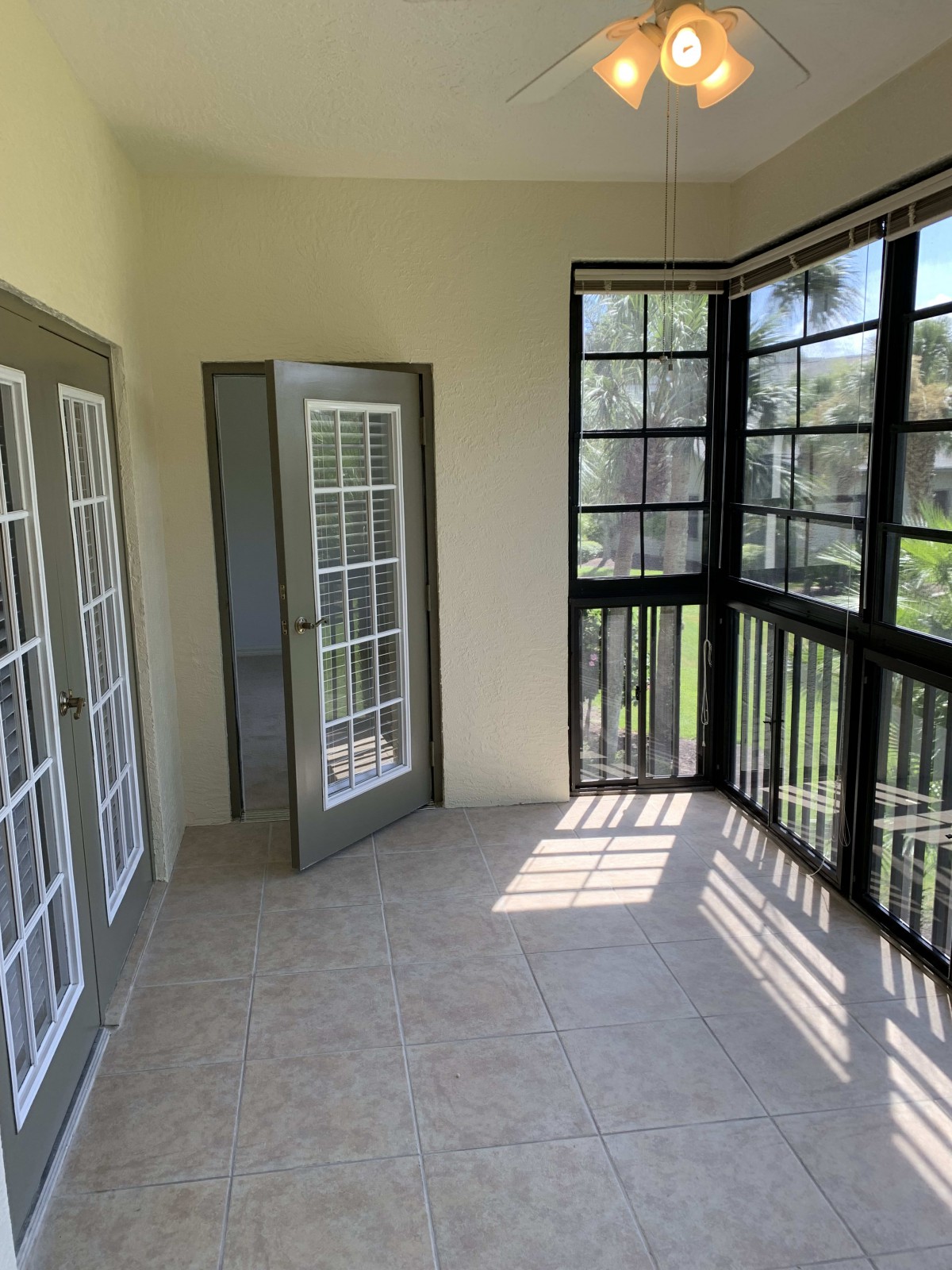 A bright sunroom with large windows and tile flooring.