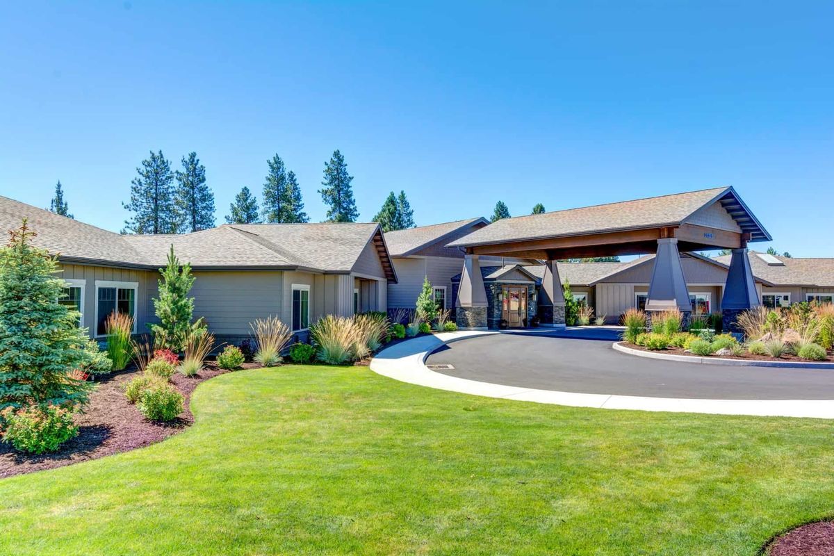 A modern house with well-maintained landscaping and a circular driveway.