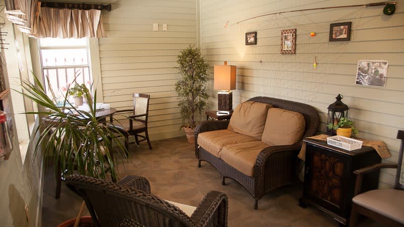 A cozy living room with a sofa, lamp, table and chairs, adorned with an indoor plant and wall decor.