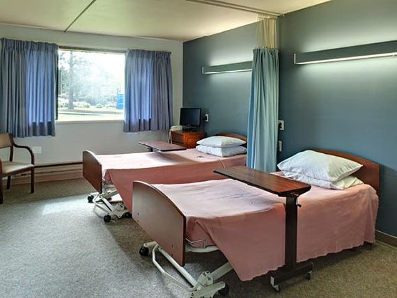 A hospital room with two patient beds and a window providing natural light.