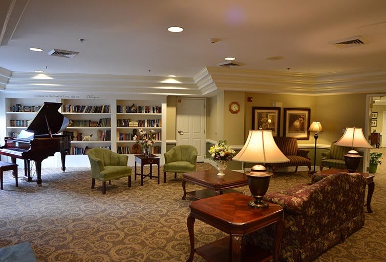 A cozy living room with a library section, featuring comfortable seating and warm lighting.