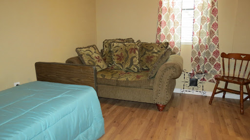 A cozy living space featuring a decorative couch with pillows and a window adorned with colorful curtains.