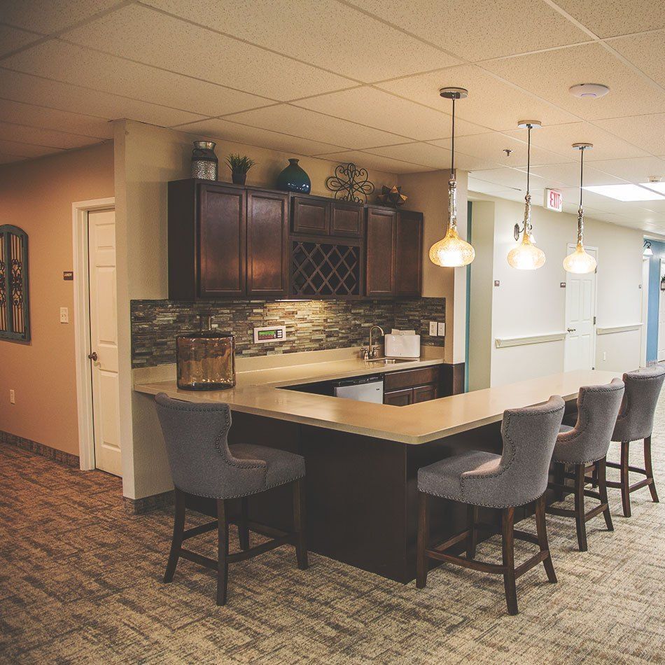 A modern kitchen with a bar area featuring pendant lights and comfortable seating.