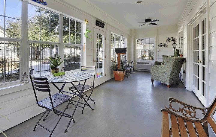 A bright sunroom with large windows, comfortable seating, and indoor plants.