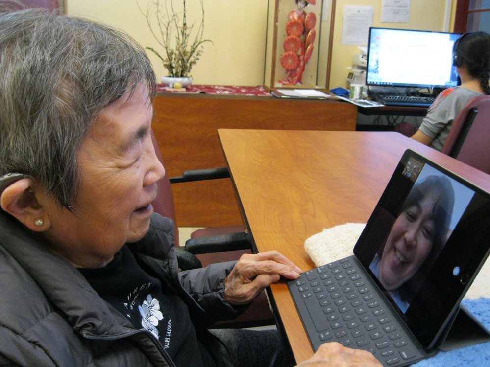 An elderly person smiling while making a video call on a tablet.