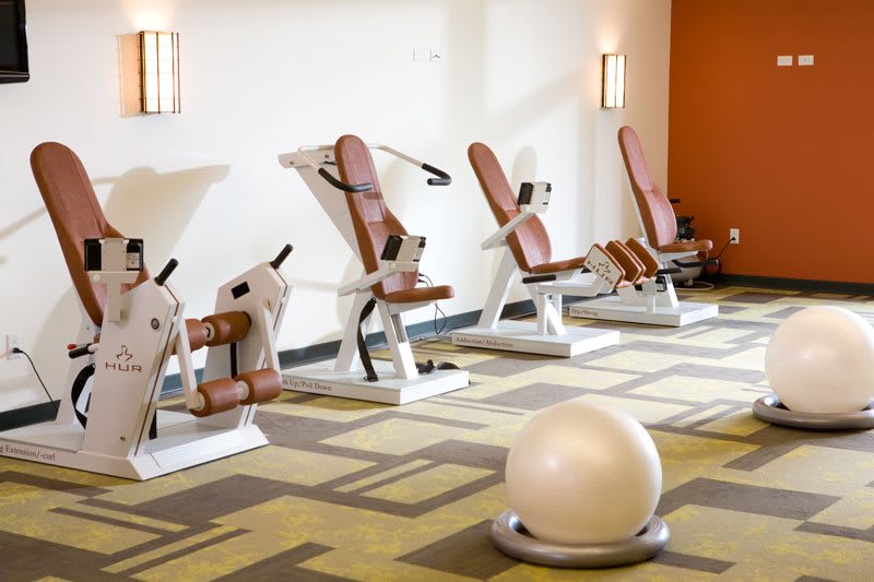 A modern gym with various exercise machines and a fitness ball.