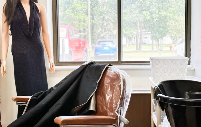 A salon interior featuring a barber chair and mannequin near a large window.
