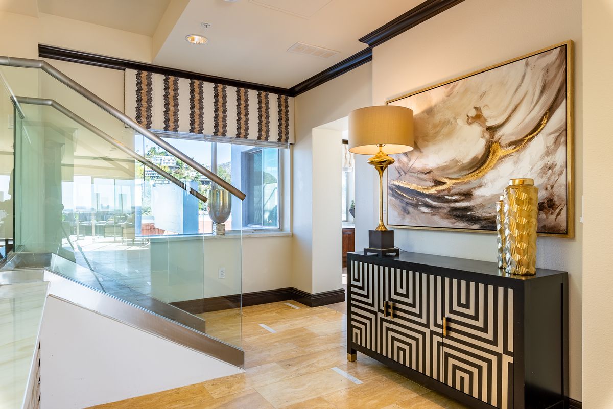 A modern living room featuring stylish furniture, a geometric console table, and eye-catching artwork beside a staircase.