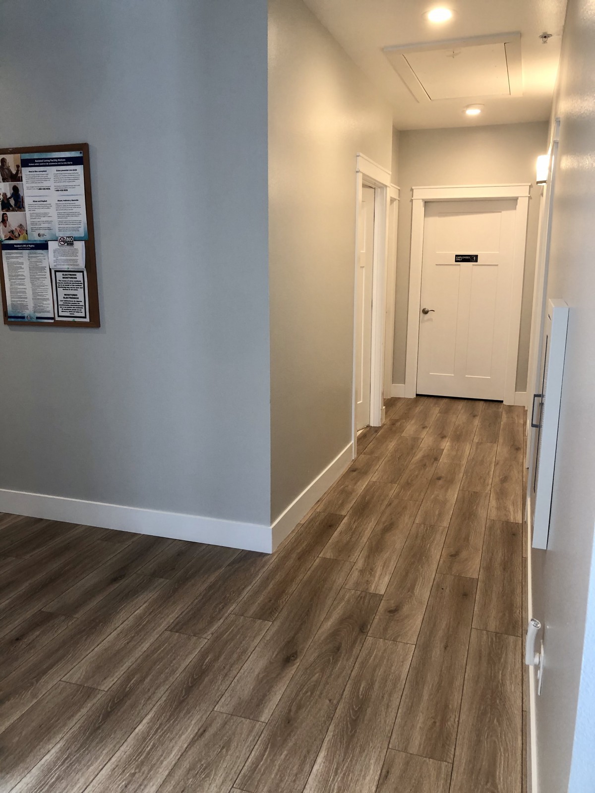 A clean and modern hallway with wooden flooring and white doors.