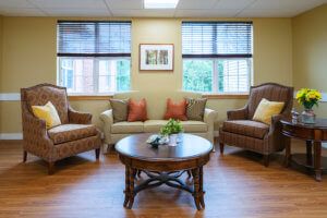 A cozy living room with two armchairs, a sofa, and a wooden coffee table in front of large windows.