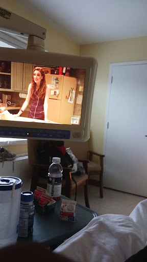 A living room scene featuring a TV displaying a woman in a kitchen setting.