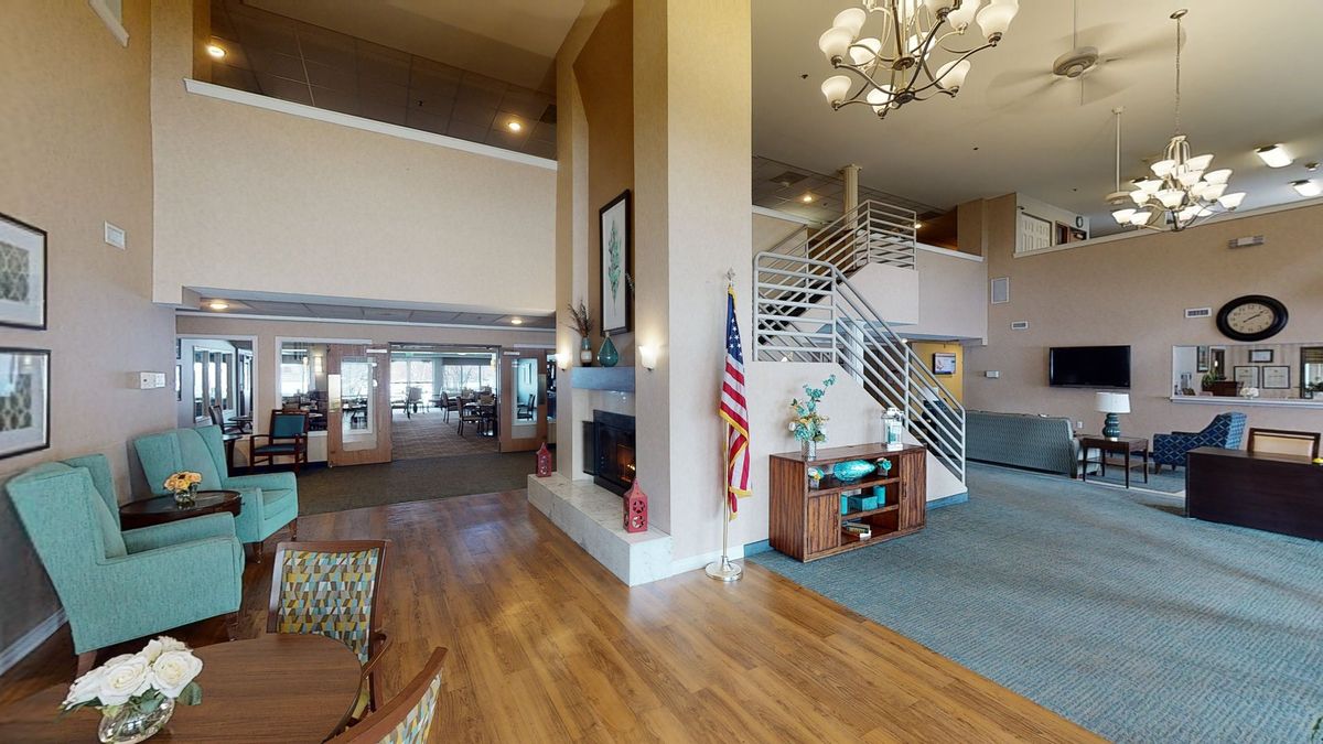 A spacious lobby area with wood flooring, a chandelier, and an American flag near the staircase.