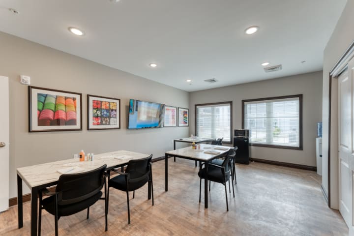 A modern conference room with tables and chairs, decorated with artwork on the walls.