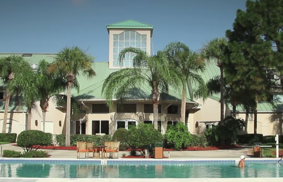 A tropical resort building surrounded by palm trees, overlooking a pool.