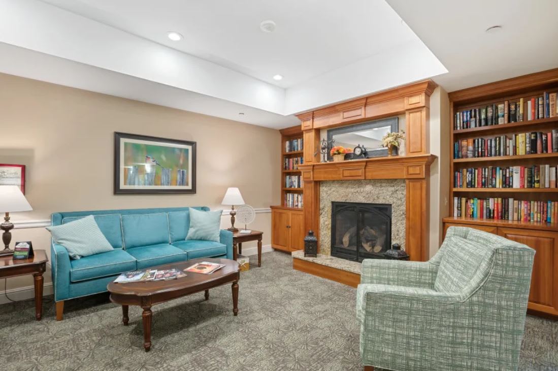 A cozy living room with a fireplace, comfortable seating, and ample lighting.