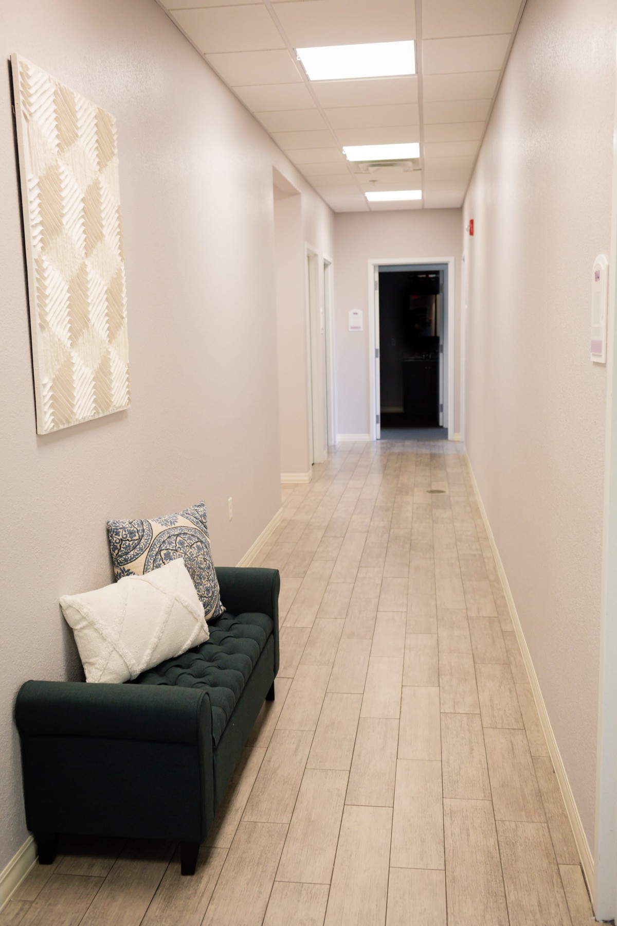 A modern hallway featuring a small sofa with pillows and artwork on the wall.