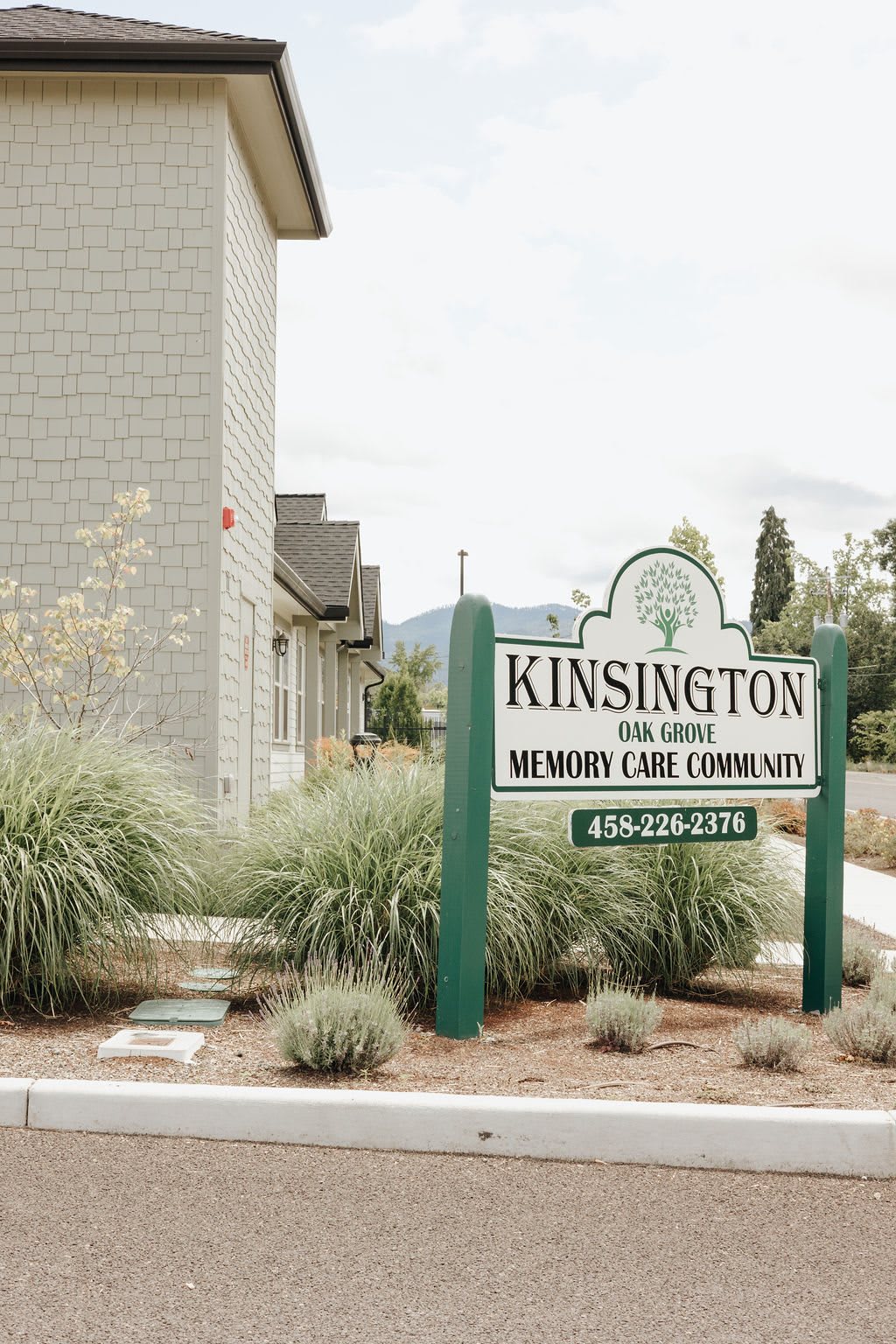Sign for Kensington memory care community near a building with landscaping.
