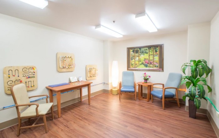 A cozy waiting room with chairs, a table, and artwork on the walls.
