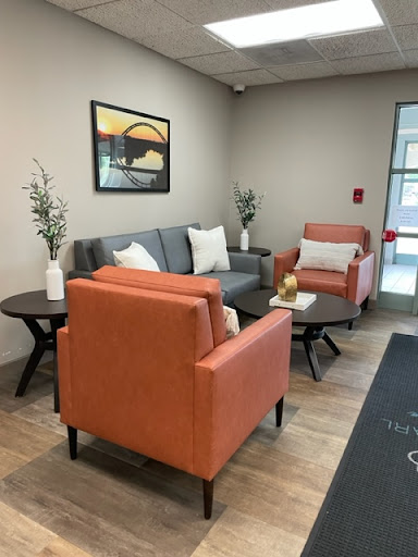 A cozy waiting area featuring modern furniture, with an inviting atmosphere created by the use of soft colors and decorative plants.