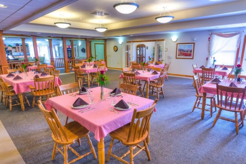 A cozy dining room with pink tablecloths and wooden furniture, set up for a meal.