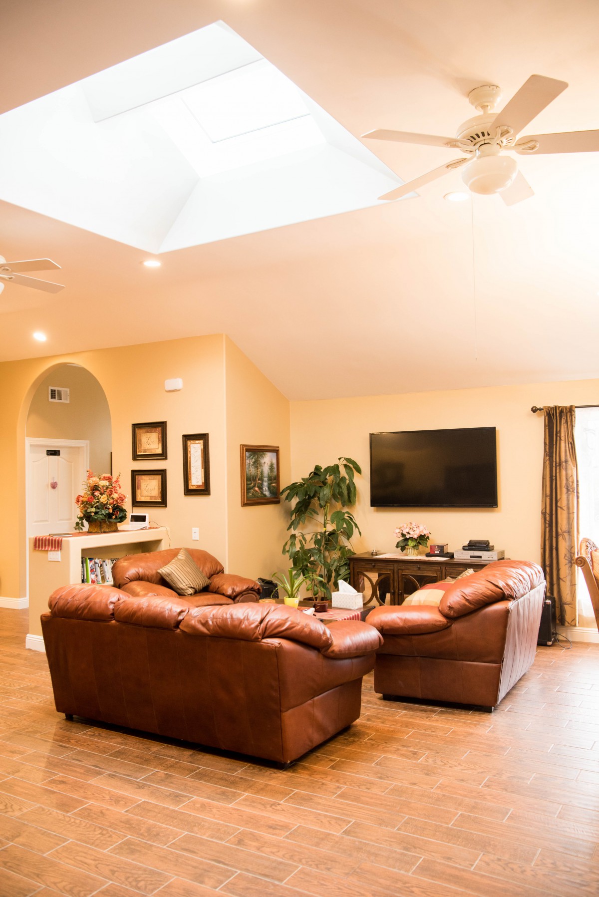 A cozy living room with leather sofas, a large television, and modern decor.
