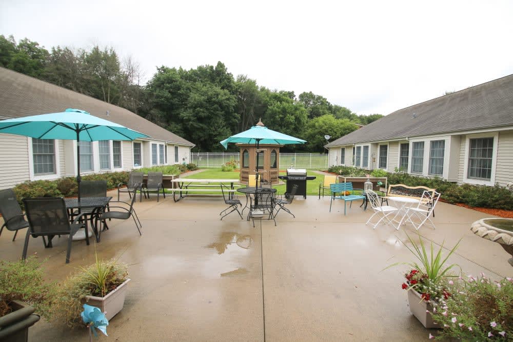A patio area with tables, chairs, and umbrellas between buildings.