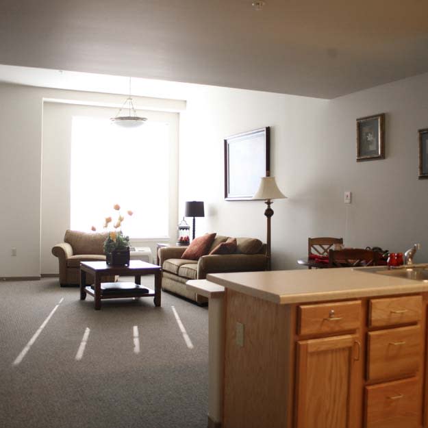 A cozy living room with a sofa, coffee table, and a large window.