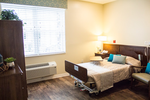 A well-lit hospital patient room featuring a bed, bedside lamp, and window.