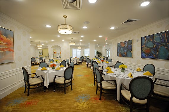 A formal dining room with elegantly set tables and comfortable chairs.